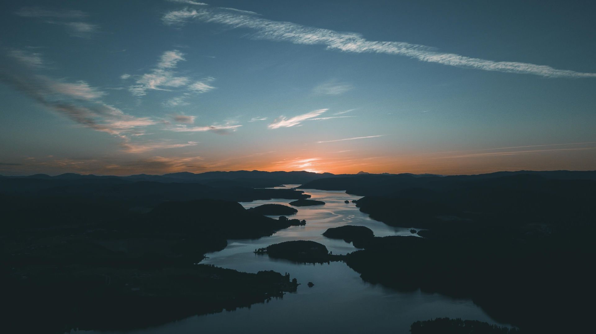 A breathtaking aerial shot showcasing a calm river winding through hills at sunset, with a vivid sky.