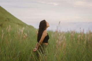 A woman stands in the lush fields of Anton Valley, Panama, basking in the natural beauty.