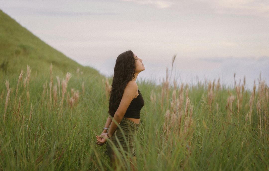 A woman stands in the lush fields of Anton Valley, Panama, basking in the natural beauty.