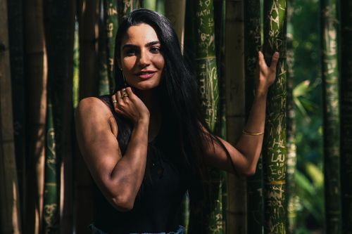 Stunning portrait of a woman posing elegantly in a lush bamboo forest.