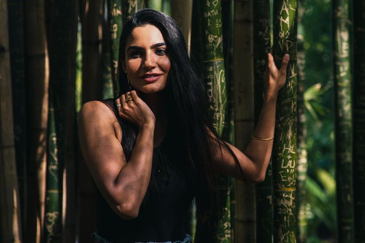 Stunning portrait of a woman posing elegantly in a lush bamboo forest.