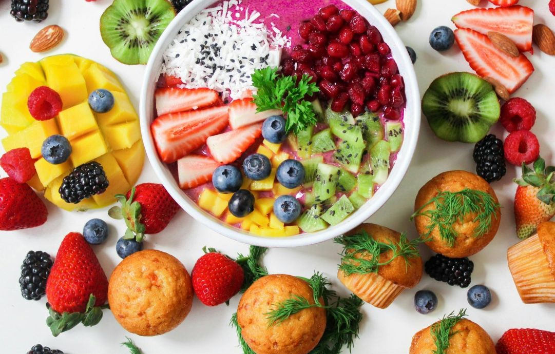Vibrant smoothie bowl topped with assorted fresh fruits and muffins, perfect for a healthy snack.