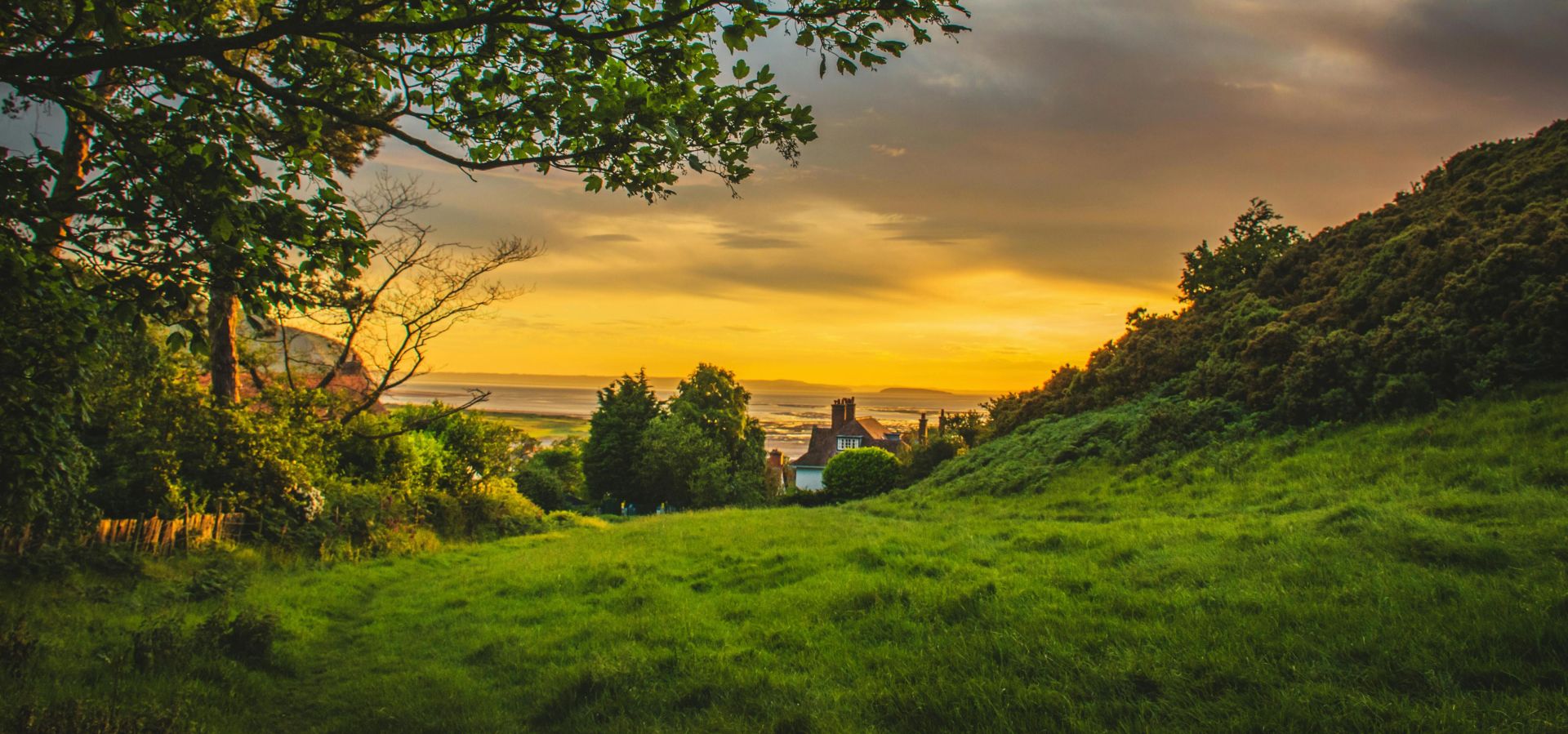 A picturesque sunset over the lush, green countryside of Deganwy, Wales, capturing nature's beauty.